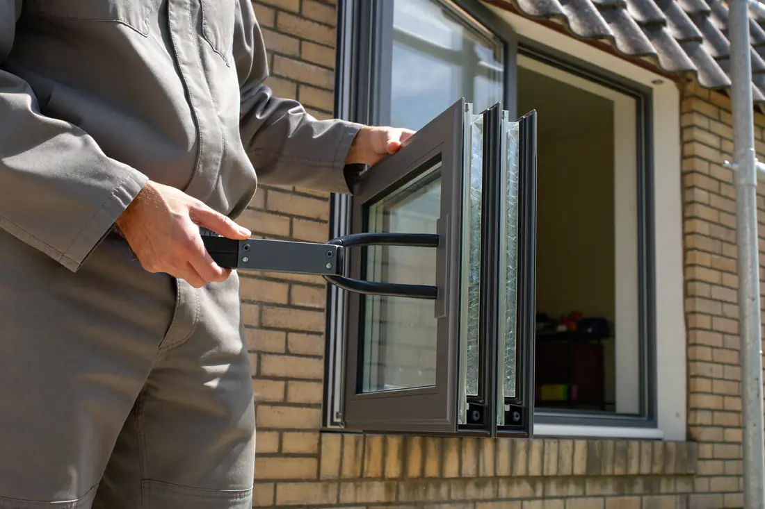 Glaszetter tilt met een zuignap een ruit isolatieglas in een kozijn