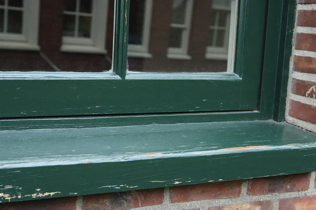 Vers geschilderd donkergroen houten kozijn met stopverf en roeden op een jaren dertig woning