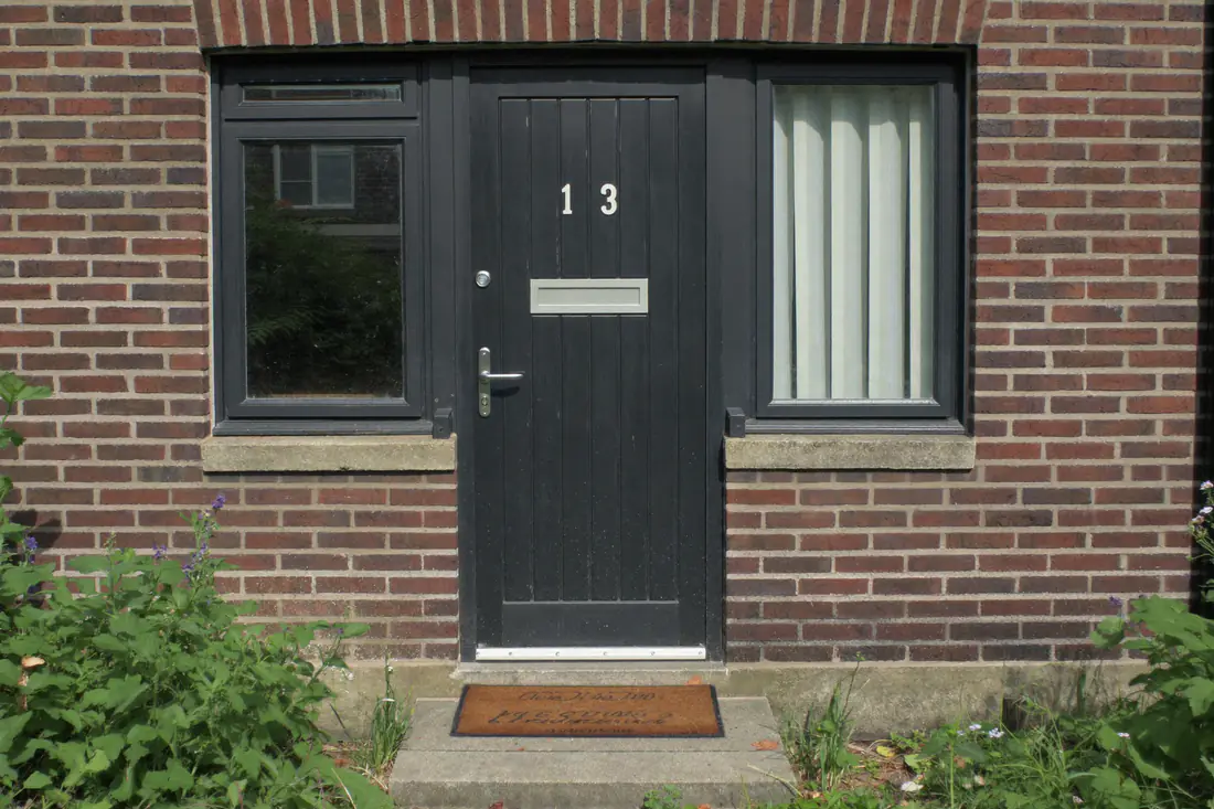 Nieuwe antracietkleurige voordeur met zijlicht in een bakstenen rijwoning